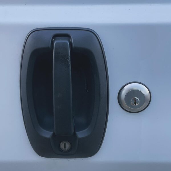 Close-up of a black vehicle door handle and silver lock on a white background.
