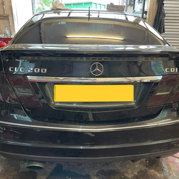 Rear view of a black Mercedes-Benz CLC 200 CDI in a garage with a yellow license plate.