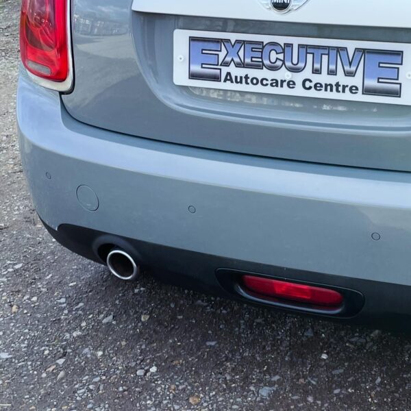 Rear view of a gray car's bumper and partial license plate.