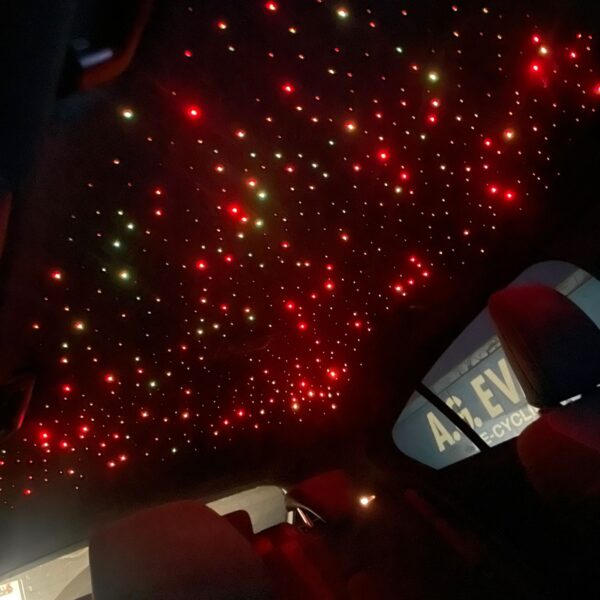 A car interior ceiling featuring red and white LED lights resembling stars.