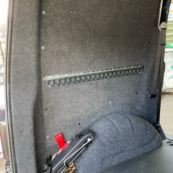 Interior view of a vehicle's cargo area with grey felt-covered walls and a black rubber floor.