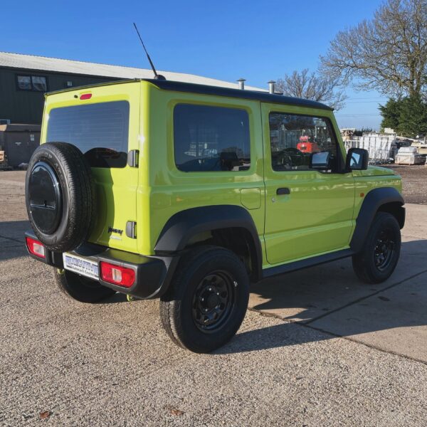 Bright green compact SUV with a spare tire mounted on the back, parked on a gravel surface under a clear blue sky.