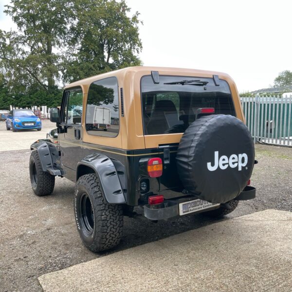 Rear view of a black and tan Jeep with a spare tire cover labeled "Jeep."