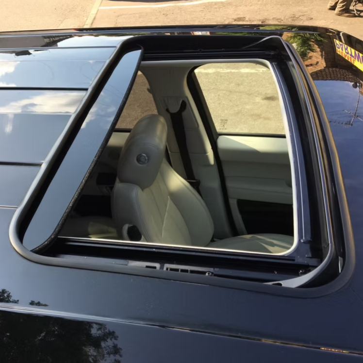 Open sunroof of a black car revealing a light gray leather passenger seat.